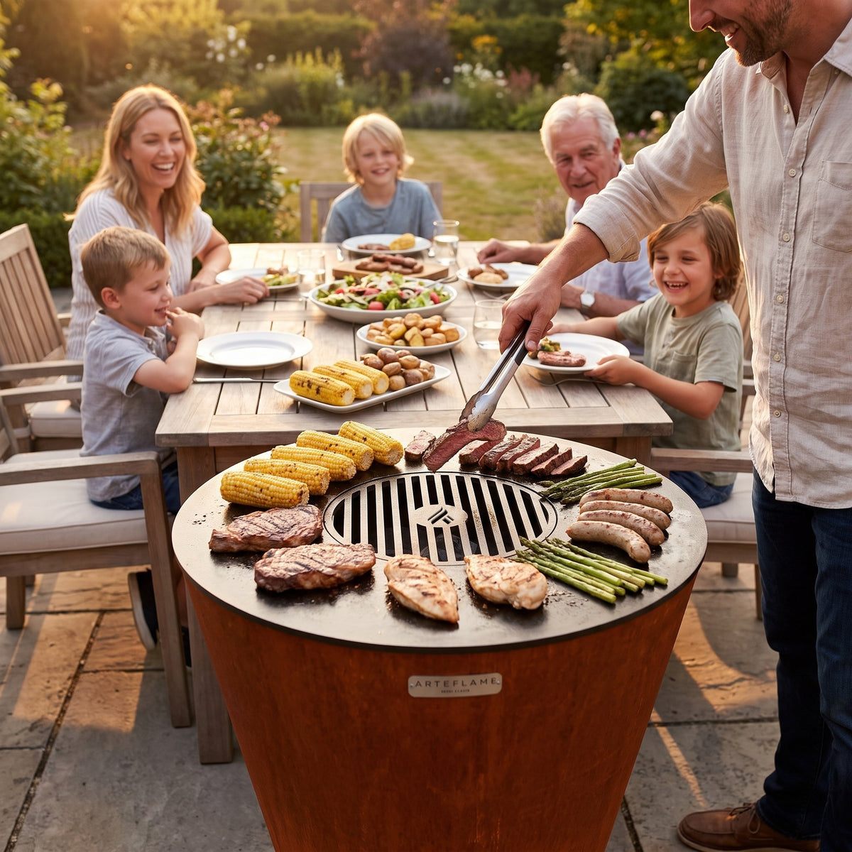 Family at a table around an Arteflame ONE30 grill with food on the cooktop