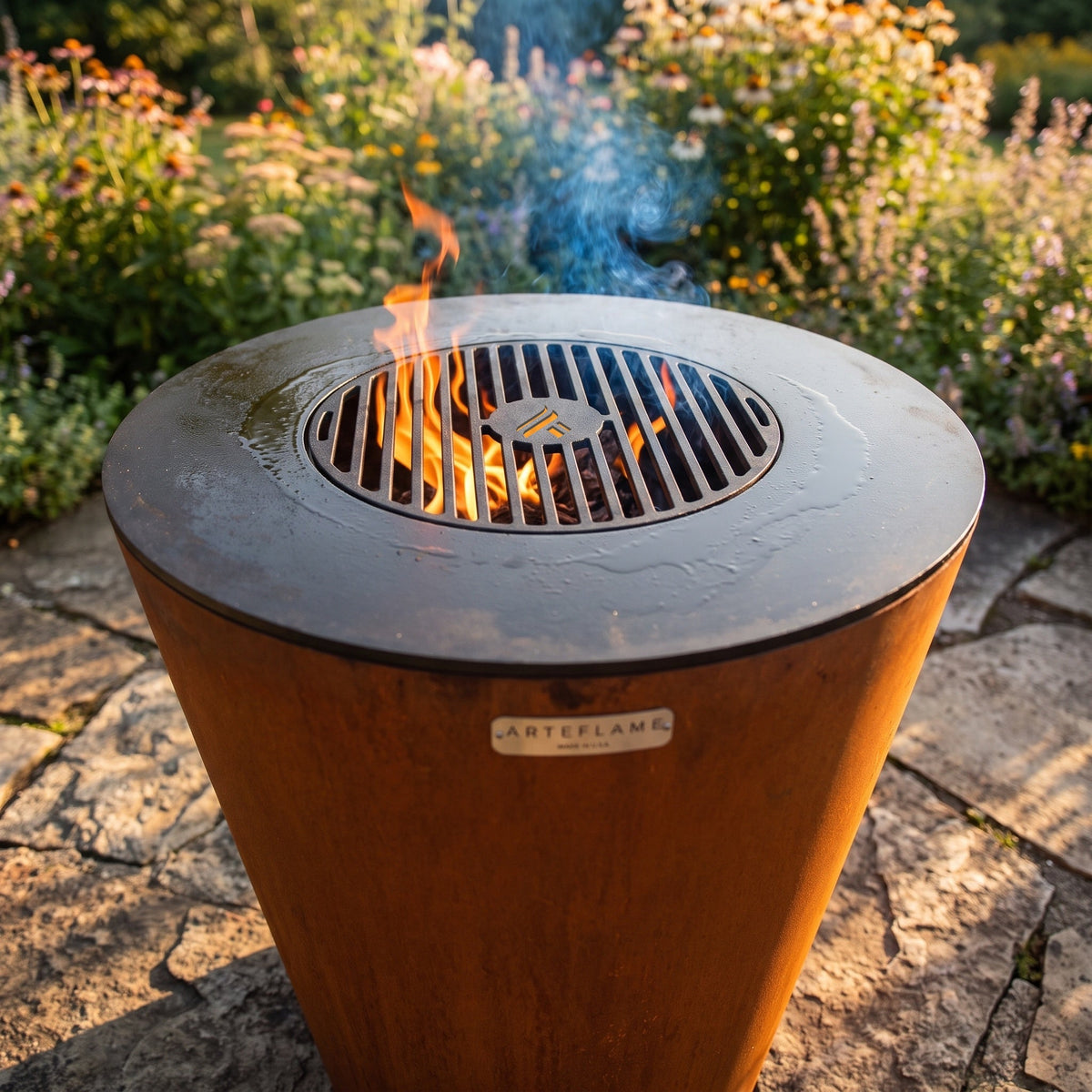 Arteflame ONE30 with the grill grate over the fire in a garden